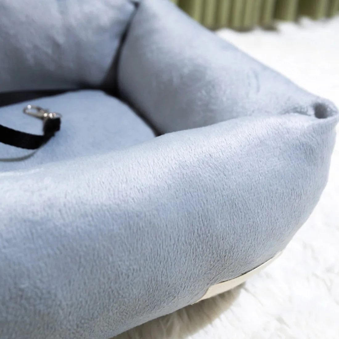 Close-up of the grey plush rim and the black strap with a metal clip inside the seat